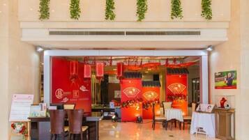 Vestíbulo de hotel con mostrador de recepción, zona de estar y elementos decorativos, incluyendo faroles rojos y plantas verdes.