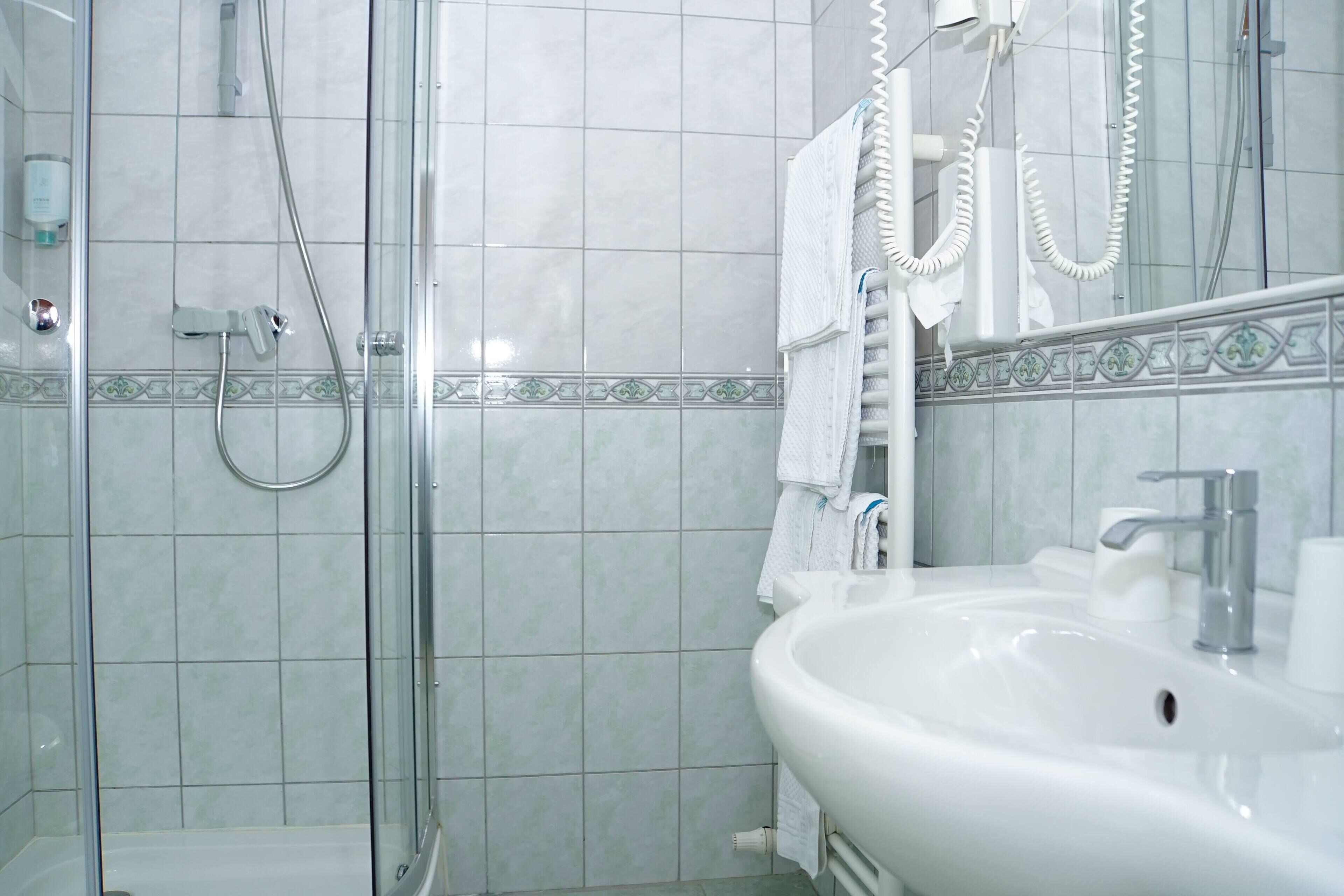 A bathroom with a glass-enclosed shower, a white sink, and a tiled backsplash.