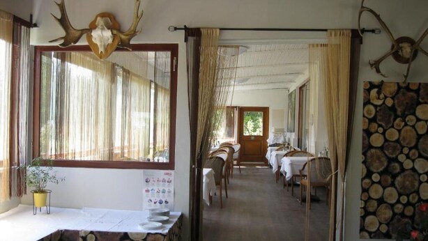 Un comedor con mesas y sillas, techo de madera y una ventana con cortinas.