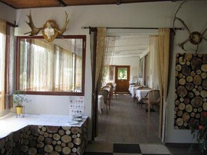 A dining area with tables and chairs, a wooden ceiling, and a window with curtains. - Hotel Hudelist (Krumpendorf am Woerther See)
