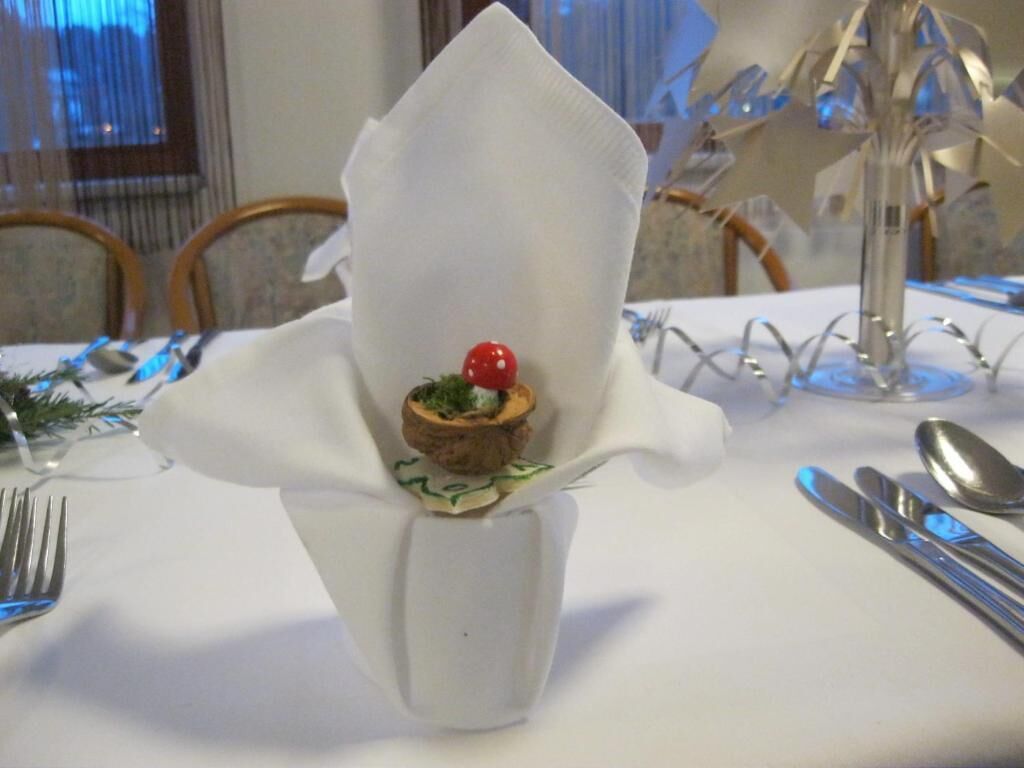 A table set with a white napkin, a glass vase, and a small dessert.