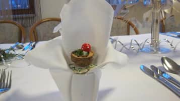 A table set with a white napkin, a glass vase, and a small dessert.