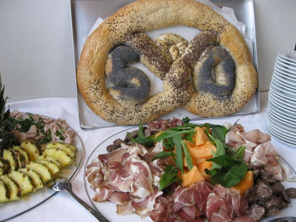 Une table avec un bretzel, des tranches de viande et un plat de légumes.