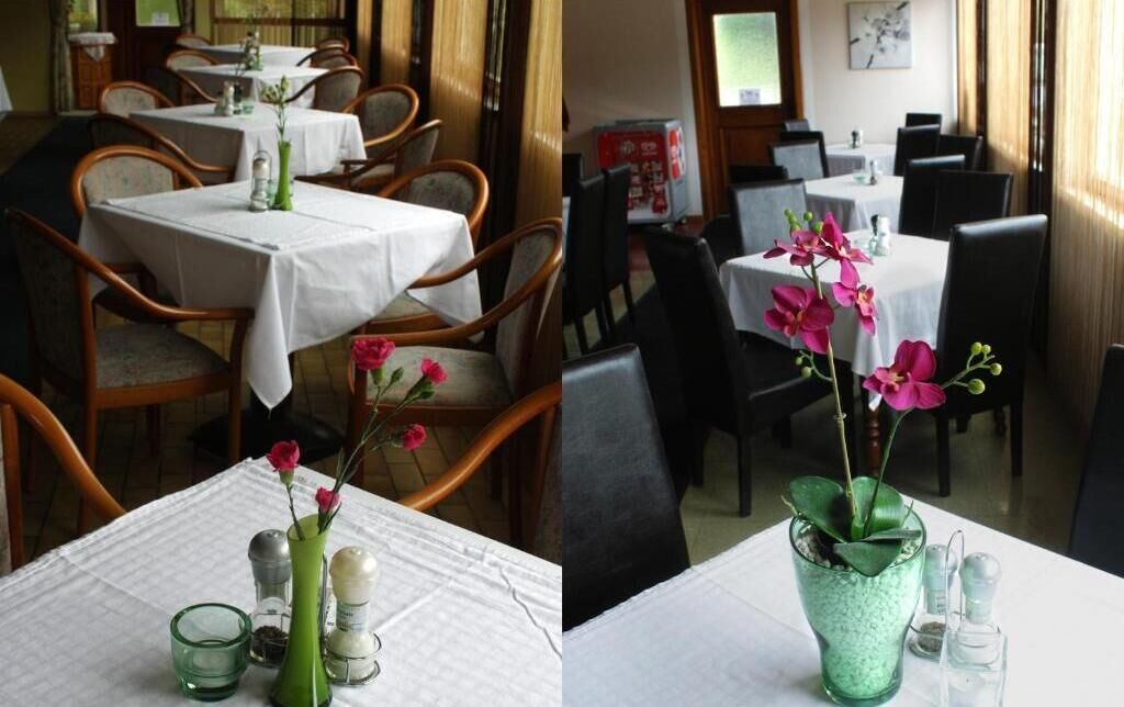 A restaurant with tables set for dining, featuring a green vase with flowers and salt and pepper shakers.