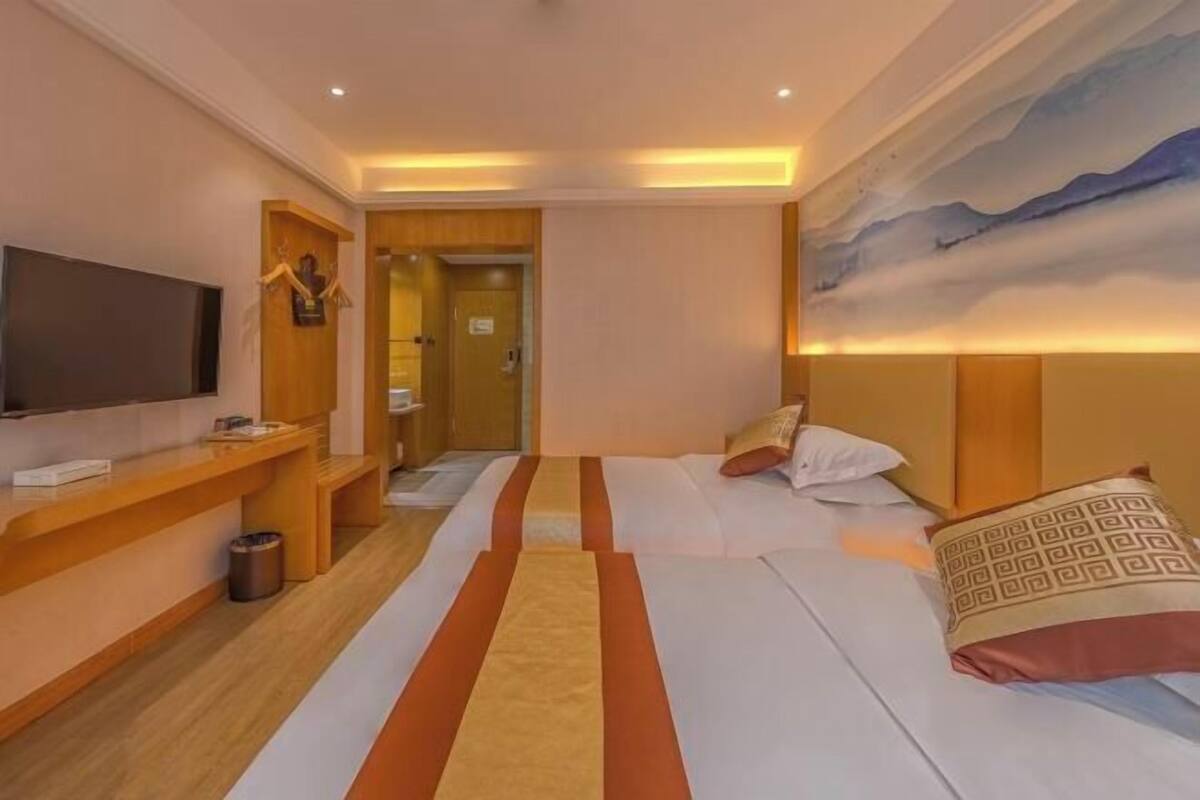 Ein Hotelzimmer mit Bett, Fernseher, Schreibtisch und einem Bild an der Wand.