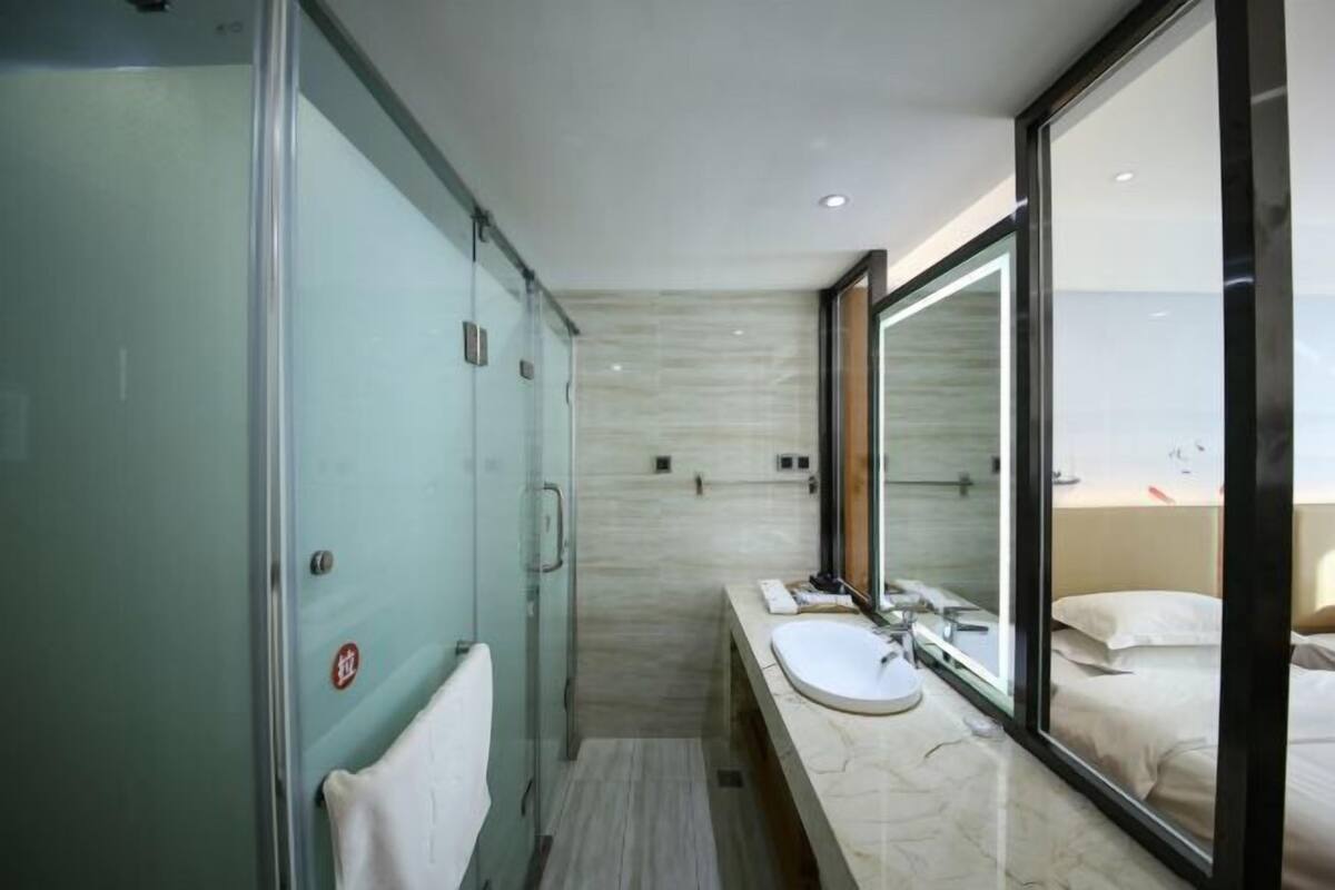 Ein modernes Badezimmer mit einer Duschkabine aus Glas, einem großen Spiegel und einem мраморному Waschbecken.