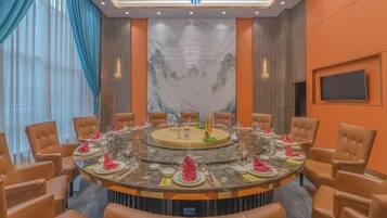 A conference room with a round table, chairs, and a large screen.
