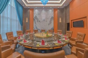 Un salón de conferencias con una mesa redonda, sillas y una pantalla grande.