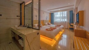 Habitación de hotel con una cama grande, baño independiente con tocador de mármol y zona de estar con una mesa y sillas.