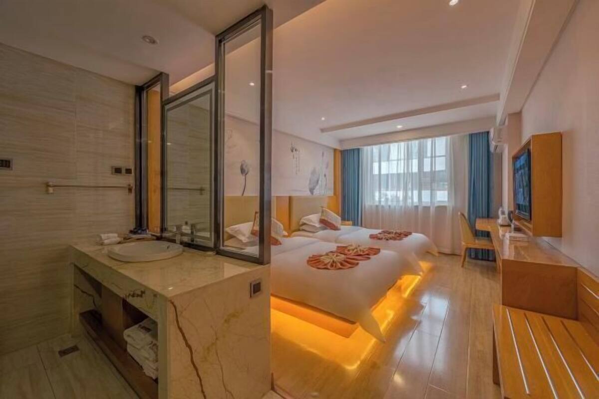 Ein Hotelzimmer mit einem großen Bett, einem eigenen Badezimmer mit Marmorwaschtisch und einer Sitzecke mit Tisch und Stühlen.