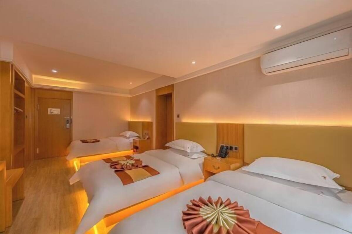 Ein Hotelzimmer mit zwei Betten, einem Holzschrank, einem Nachttisch mit Lampe und einer Wandklimaanlage.