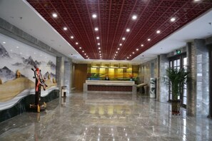 A spacious lobby with a reception desk, a large mural, and a polished marble floor. - Suzhou Hotel (Jiuquan)