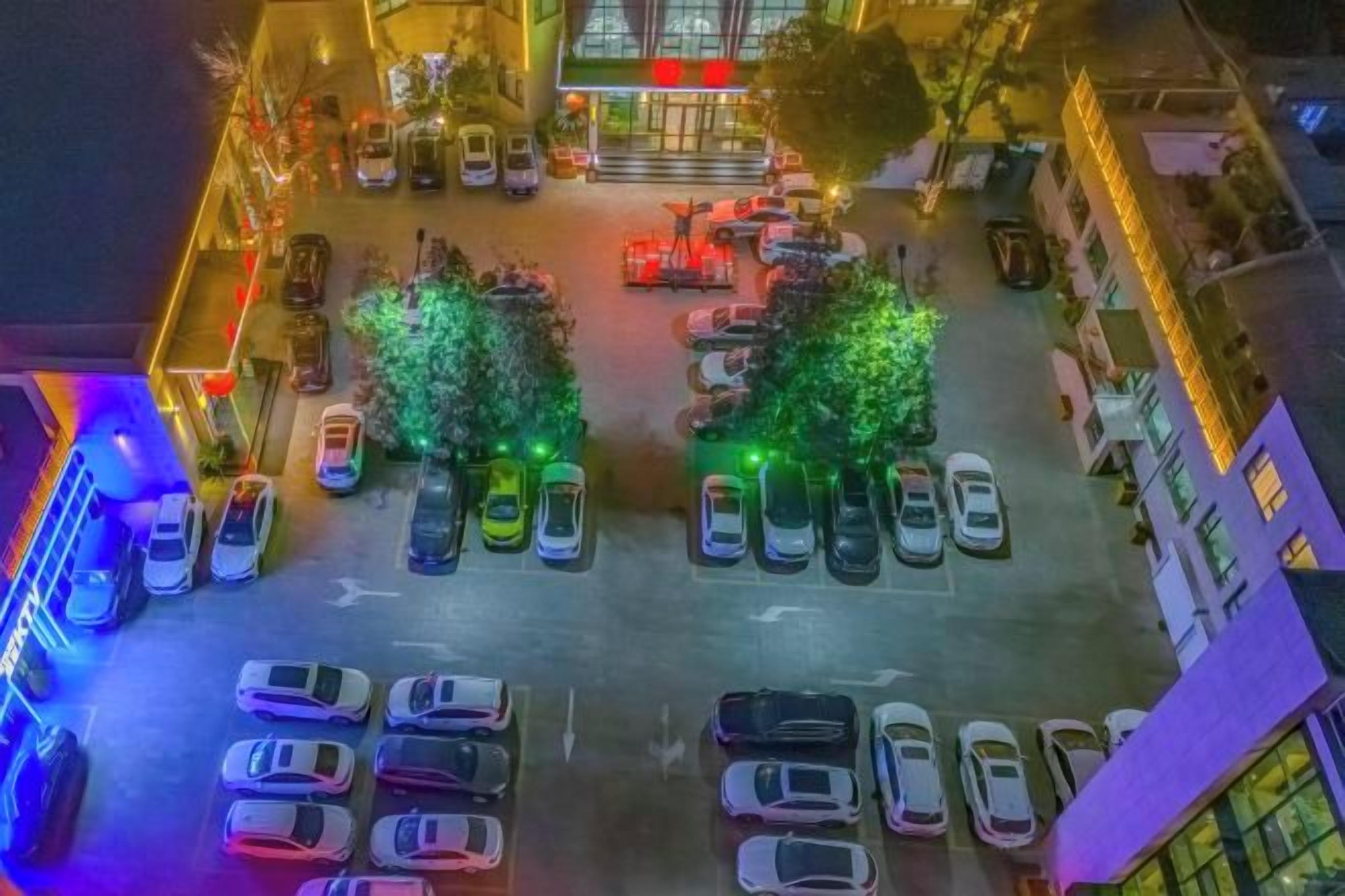 An aerial view of a parking lot with cars and trees.
