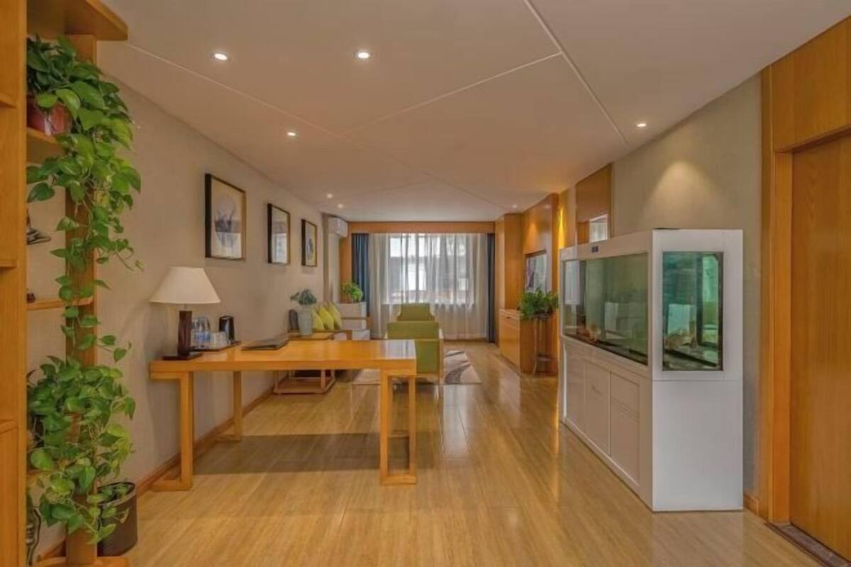 Ein modernes Wohnzimmer mit Holzboden, einem Esstisch, Stühlen, einer Couch, einem Fernseher und einem Aquarium.