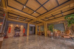Un hall d’entrée spacieux avec un plafond haut, un mur en pierre et un espace détente comprenant des fauteuils et une table.