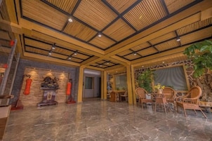Um hall espaçoso com teto alto, parede de pedra e área de estar com cadeiras e mesa.