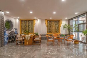 Un vestíbulo de hotel con mostrador de recepción, zona de estar y amplios ventanales.