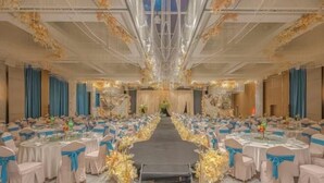 Un salón de banquetes con mesas redondas, fajines azules y un pasillo central.