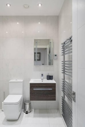 A modern bathroom with a toilet, sink, and mirror.