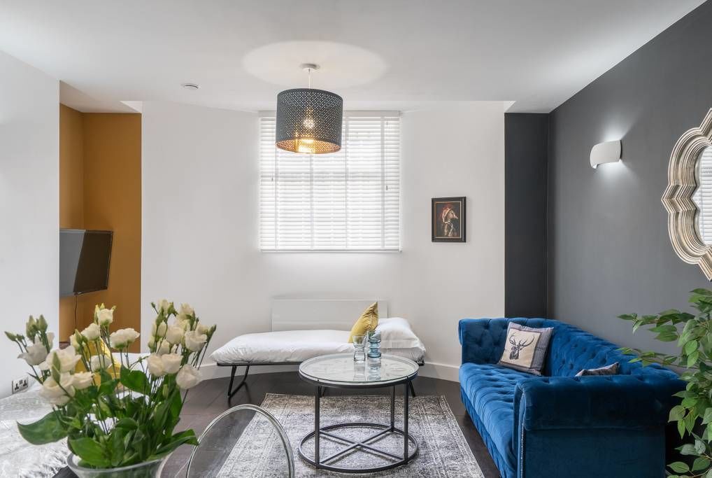 A modern living room with a blue sofa, a round coffee table, and a hanging light fixture.