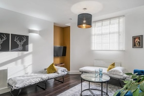 A modern living room with a sofa, a round coffee table, and a TV mounted on the wall.