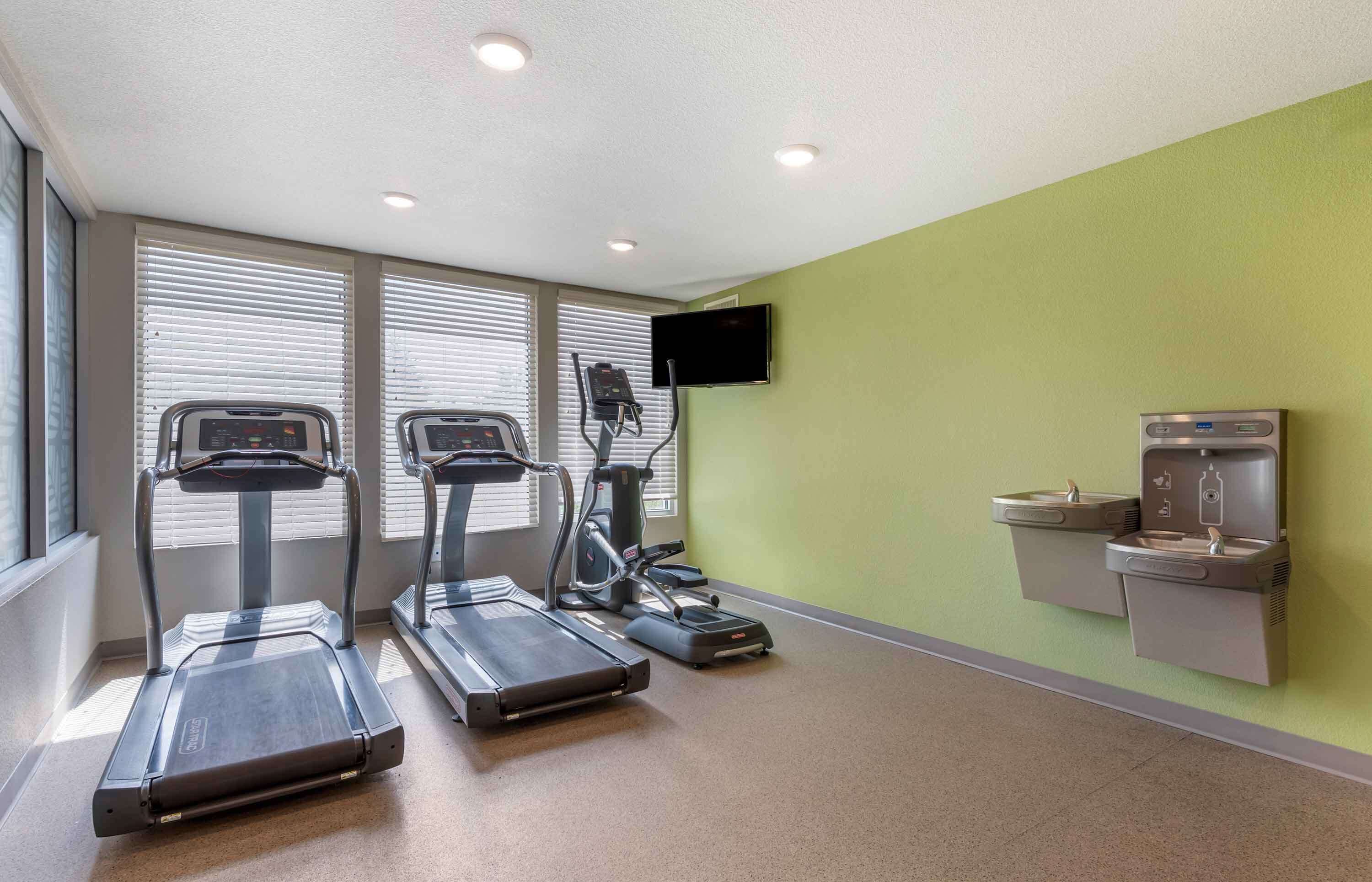 Une salle de remise en forme équipée de tapis de course, d’un vélo d’appartement et d’un écran de télévision.