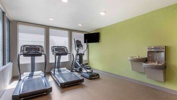 A fitness room with treadmills, a stationary bike, and a TV screen.