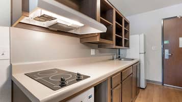Une cuisine moderne dotée d’une plaque de cuisson à induction intégrée, d’un évier en acier inoxydable et de meubles de rangement en bois.