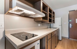 Une cuisine moderne dotée d’une plaque de cuisson à induction intégrée, d’un évier en acier inoxydable et de meubles de rangement en bois.