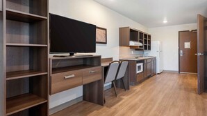 Una cocina moderna con armarios de madera, horno integrado y televisor de pantalla plana.
