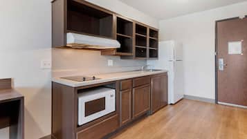 Una cocina compacta con horno integrado, microondas, lavaplatos y refrigerador.