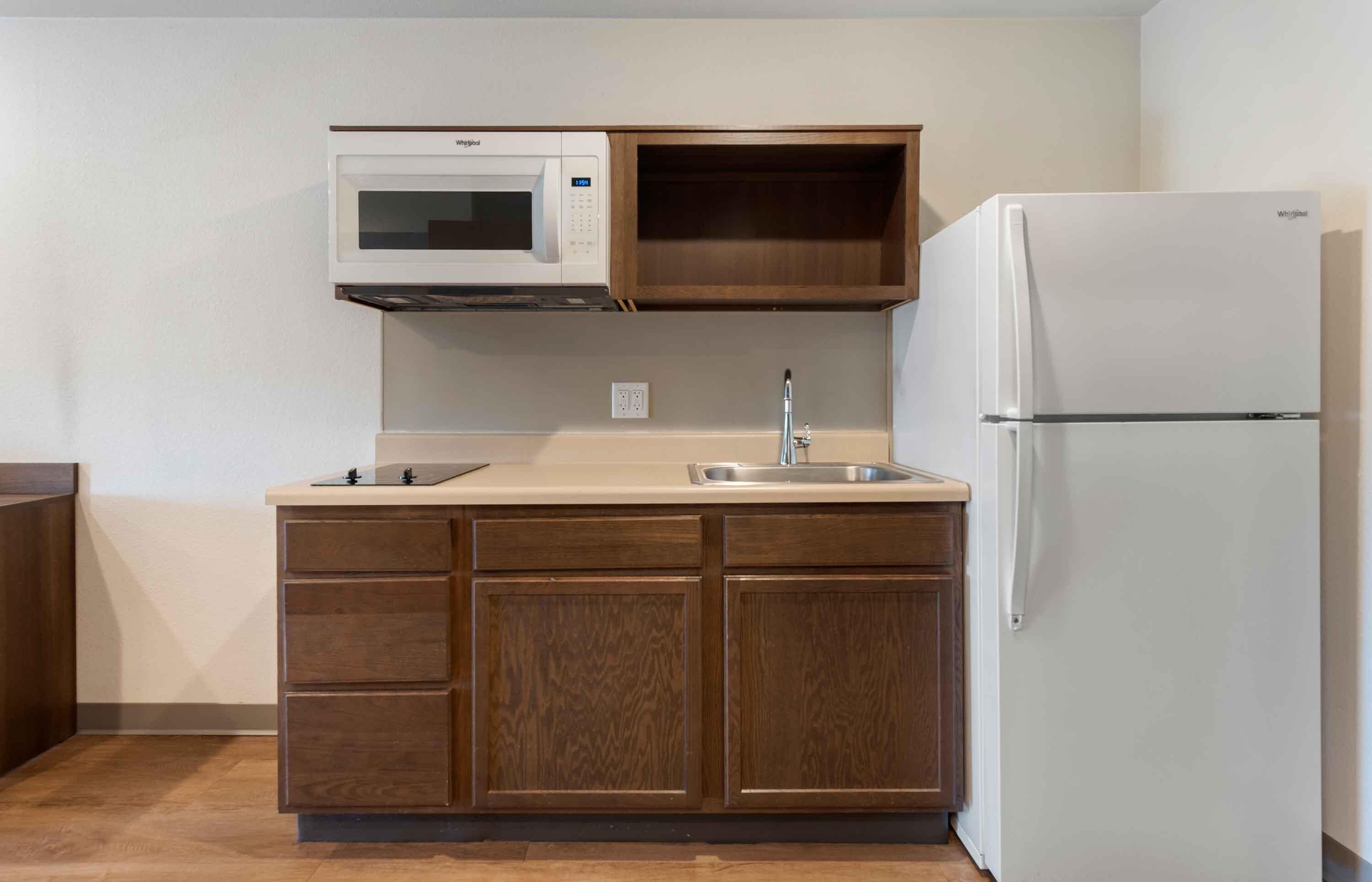 Una cocina con microondas, lavamanos y refrigerador.