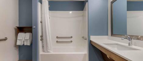 A bathroom with a bathtub, a shower, a sink, and a mirror.