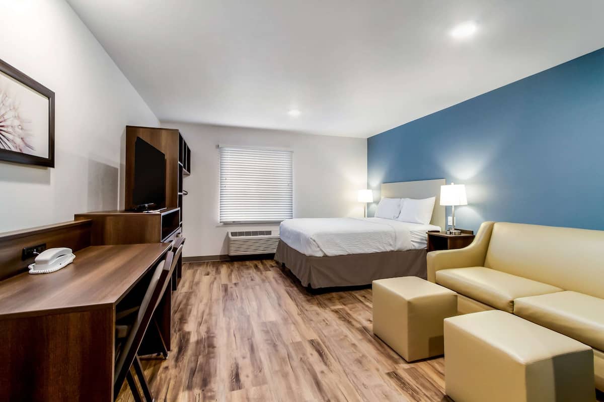 Een hotelkamer met een houten bureau, een bed, een bank en een televisie.