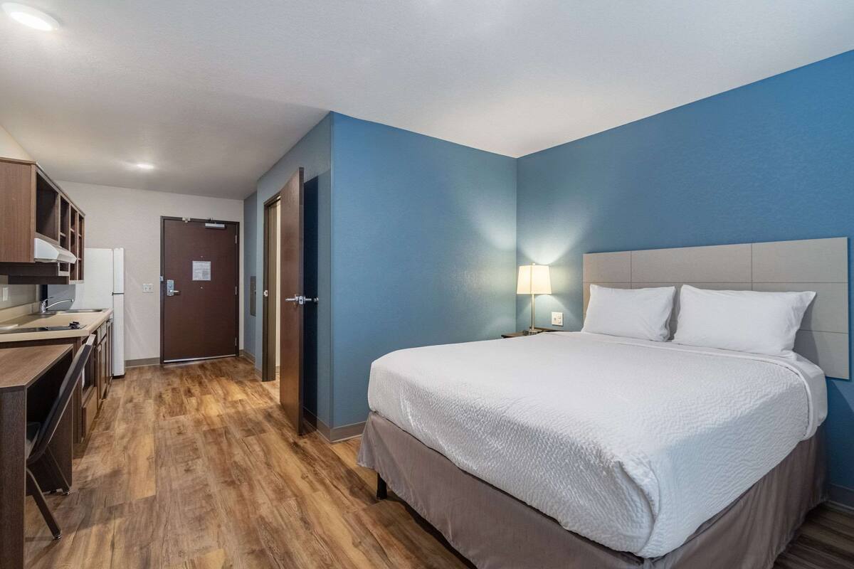 Een hotelkamer met een bed, een bureau en een kitchenette.