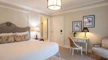 A hotel room with a large bed, a desk, a chair, and artwork on the wall.