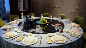 Una mesa de comedor redonda con una isla central, rodeada de sillas, dispuesta con platos, vasos y cubiertos.