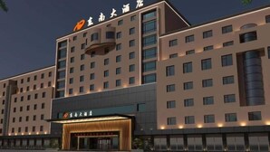 Un hotel de varios pisos con fachada moderna, que destaca por su entrada con marquesina y señalización iluminada.