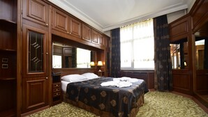 A hotel room with a large bed, wooden cabinets, a mirror, and a window with curtains. - Topkapi Hotel (Istanbul)