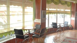A room with large windows, green curtains, and a wooden floor. There are chairs and a table. - Topkapi Hotel (Istanbul)