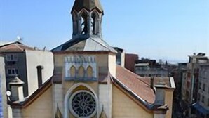 Una iglesia con un campanario, una cúpula central y una escalera que conduce a la entrada.
