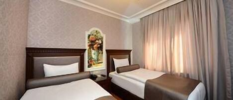 A hotel room with two beds, a nightstand, a painting, and a window with curtains.