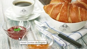 Ein Frühstückstisch mit Croissants, einer Kaffeetasse und einer kleinen Marmeladengläschen.