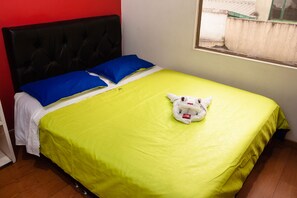 A bed with a bright green bedspread, a black upholstered headboard, and two blue pillows.