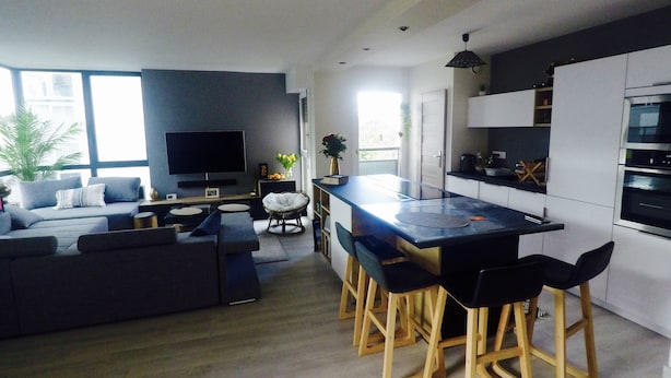 A modern living room with a large flat-screen TV, a sofa, and a dining area with bar stools. - Charming and cosy rooms (Reze)