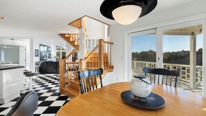 A modern kitchen with a checkered floor, wooden staircase, and large windows overlooking a balcony.