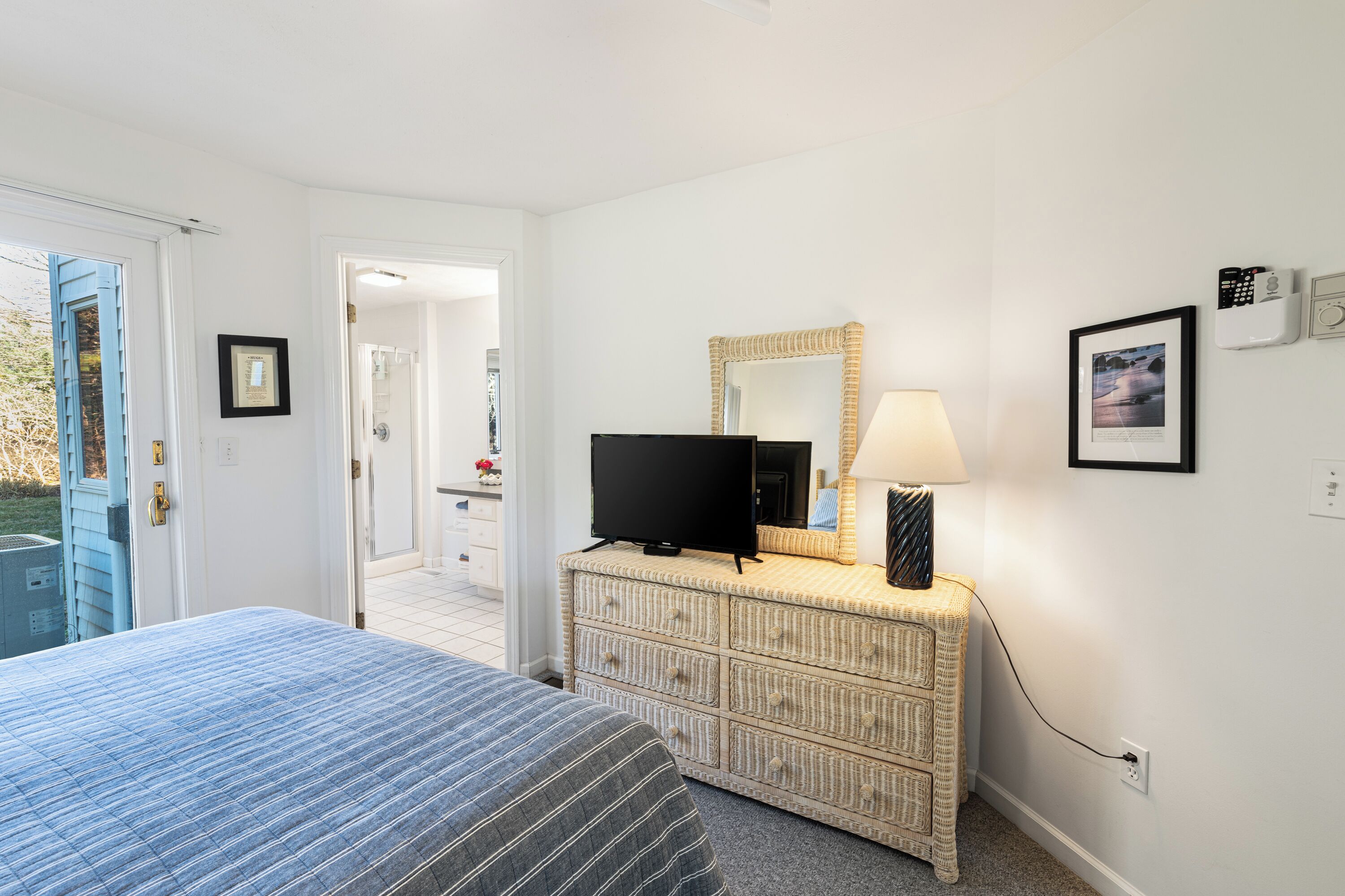 Une chambre à coucher avec un lit, un téléviseur posé sur une commode, un miroir et une lampe.