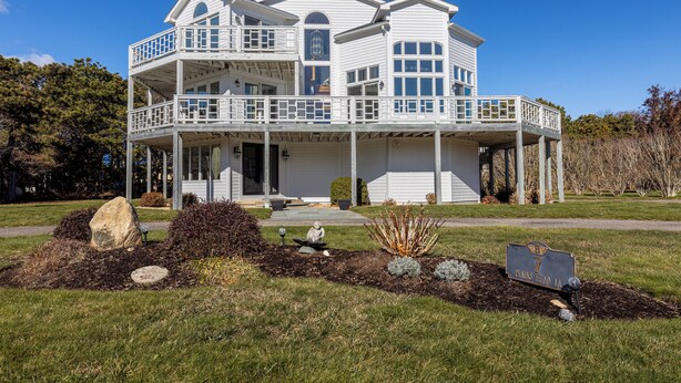 A two-story house with a balcony, a front porch, and a well-maintained lawn.