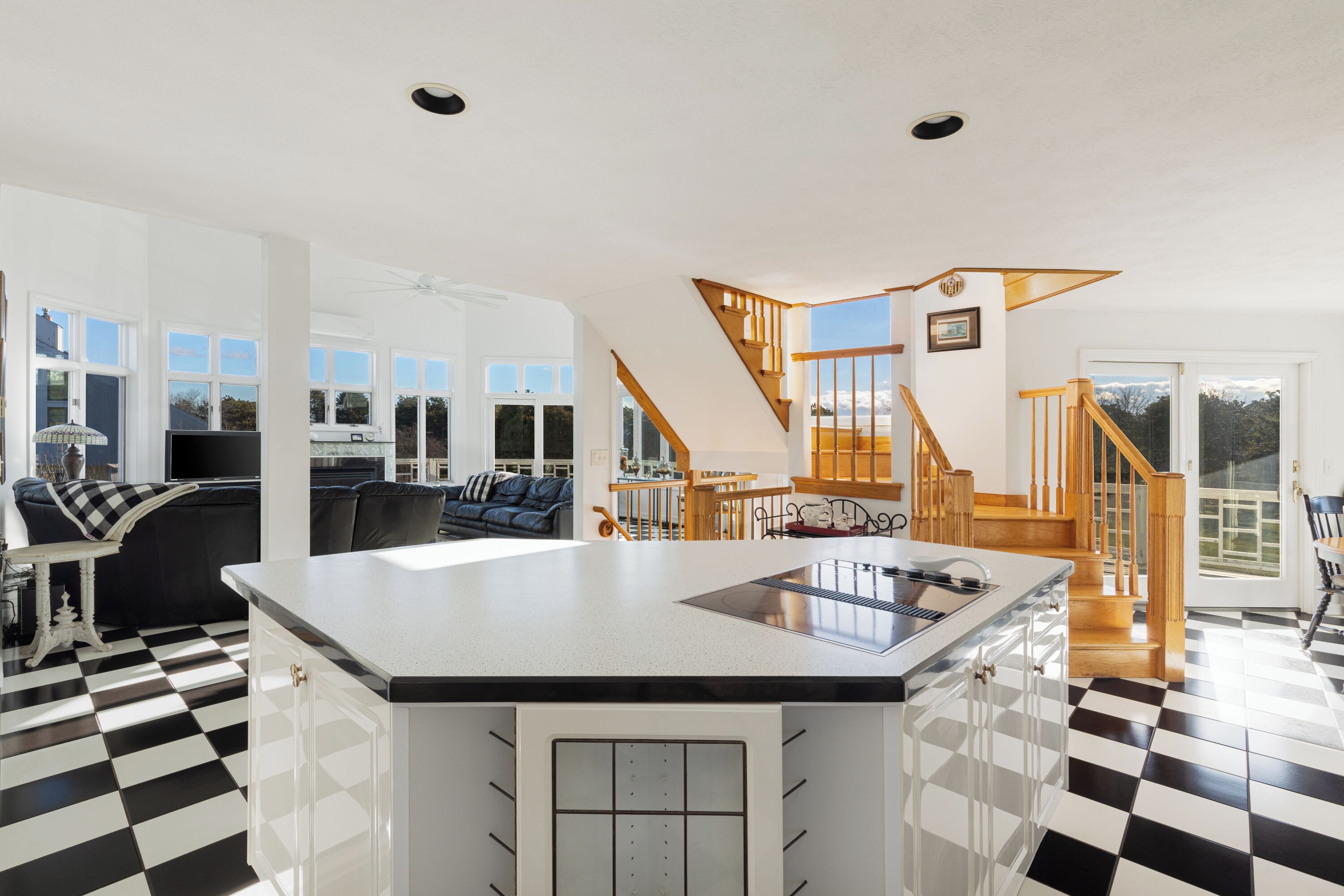 A spacious living area with a large kitchen island, a staircase leading to an upper level, and a checkered floor.