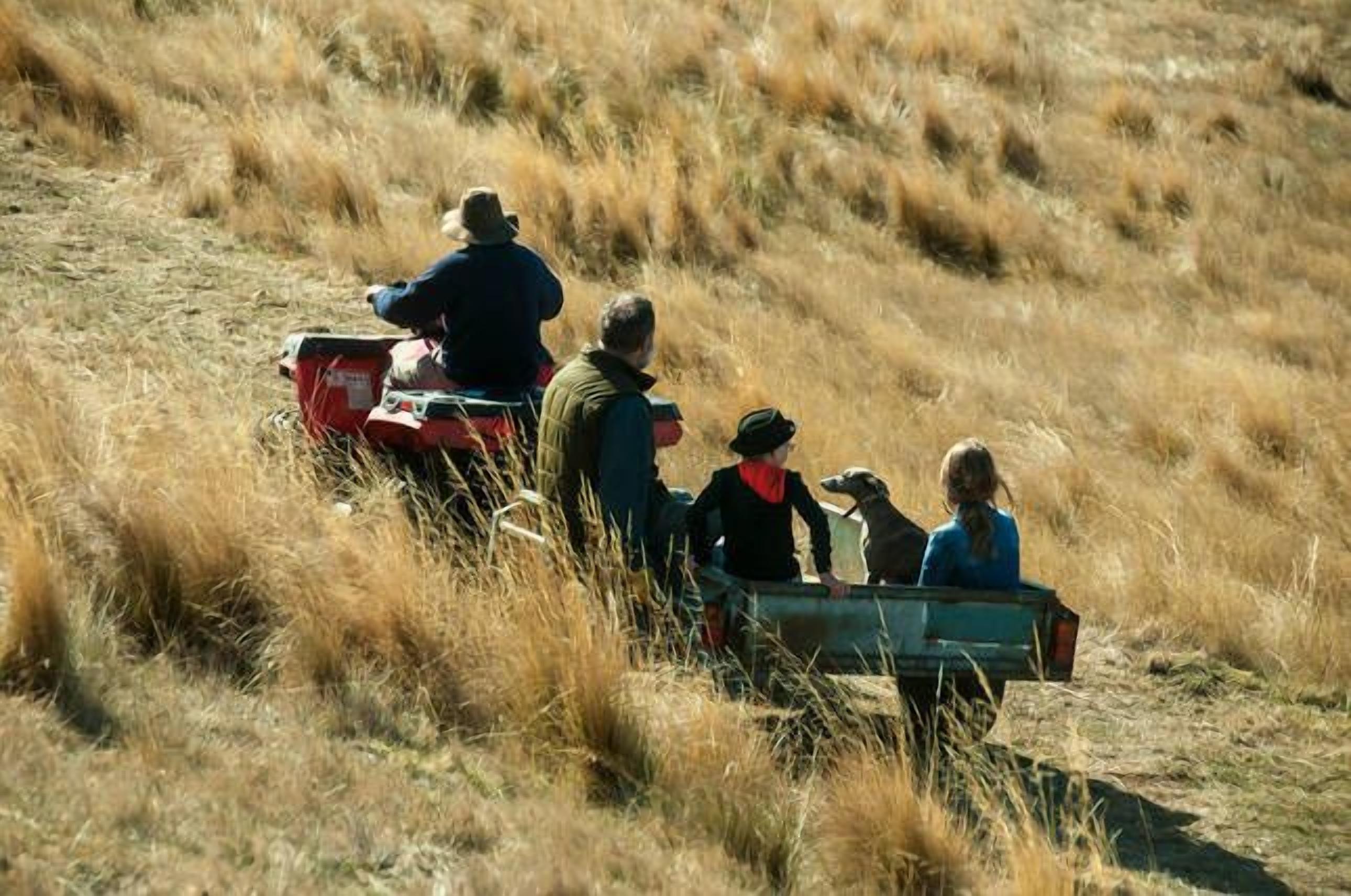 Een groep mensen in een voertuig op een grasveld.